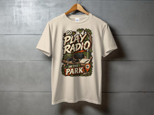 Load image into Gallery viewer, Light tan t-shirt with "Go Play Radio In The Park" graphic featuring camping gear.
