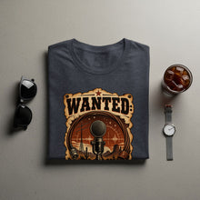 Load image into Gallery viewer, Dark gray t-shirt with a "WANTED" graphic featuring a vintage microphone and desert scene.
